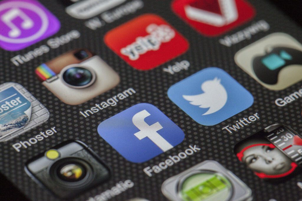 Een close-up van een smartphone, met de icoontjes van Facebook, Twitter en Instagram scherp in beeld.